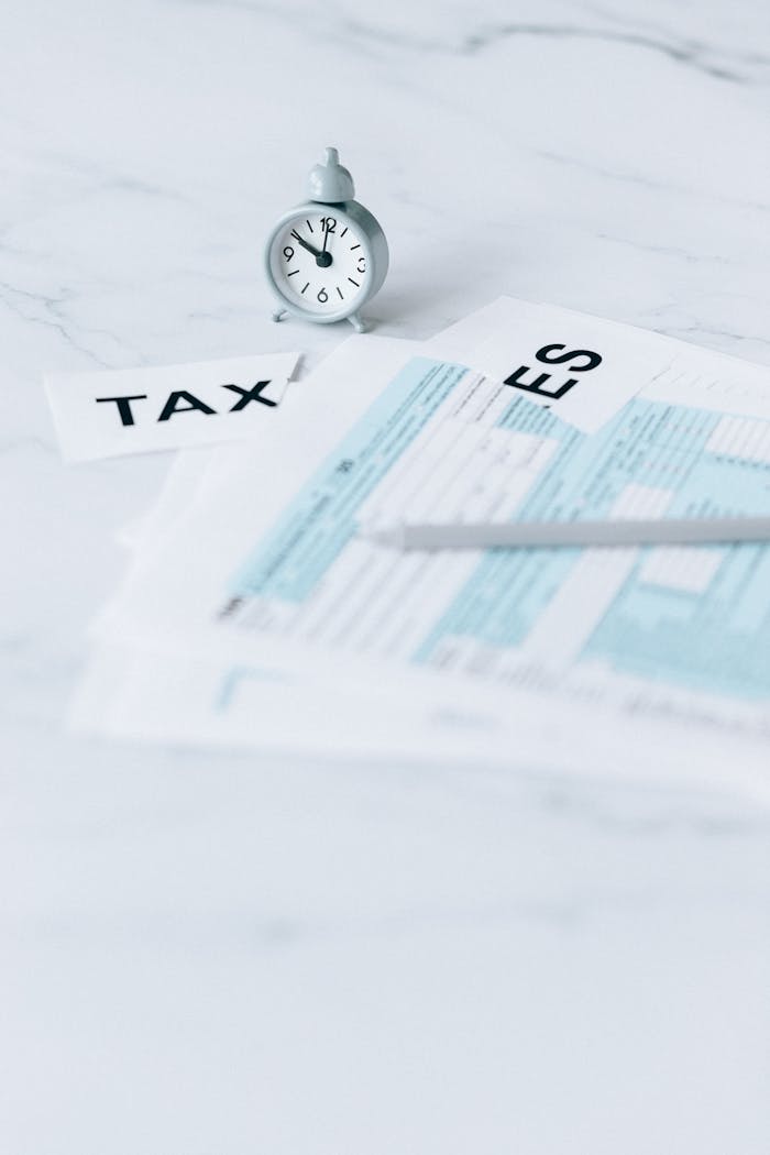 Tax documents and clock on marble, representing tax deadlines and financial concepts.